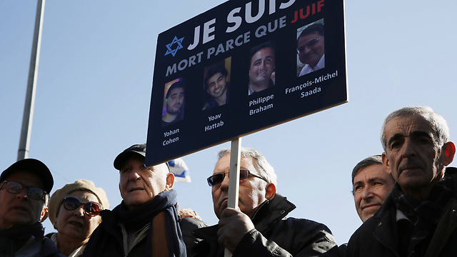 Mourners carry a banner showing the four victims of the attack. (Photo: AFP)