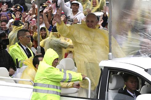 האפיפיור בכיסוי נגד גשם צהוב מעל גלימתו הלבנה (צילום: AP) (צילום: AP)