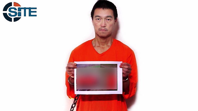 השבוי קנג'י גוֹטוֹ מחזיק בתמונה של חברו שלכאורה הוצא להורג ()