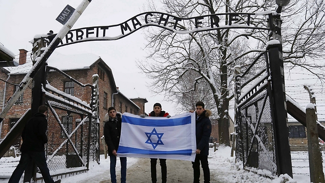 Visitors hold Israeli flag at entrance of Auschwitz (Photo: Reuters)