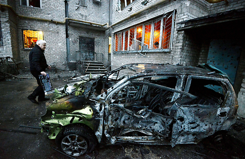 אדם עומד ליד מכוניתו לאחר שנהרסה מירי ארטילרי בעיר דונייצק שבמזרח אוקראינה (צילום: AFP) (צילום: AFP)