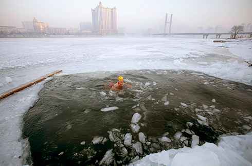 שחיין שוחה במים קרים לאחר ששבר את הקרח בנהר הסונג'ואה הקפוא שבסין (צילום: רויטרס) (צילום: רויטרס)