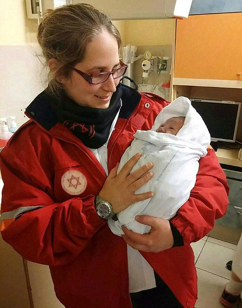 Paramedic holds newborn . (Photo: Jerusalem MDA Spokesman's Unit)