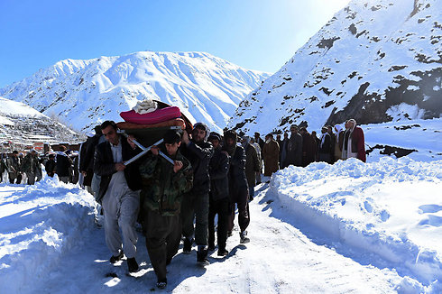 גברים אפגנים נושאים גופה של אדם שנהרג במפולת שלגים במחוז פאנג'שיר. יותר מ-200 בני אדם נהרגו בסדרת מפולות שלגים בארבעה מחוזות בצפון-מזרח אפגניסטן (צילום: AFP) (צילום: AFP)
