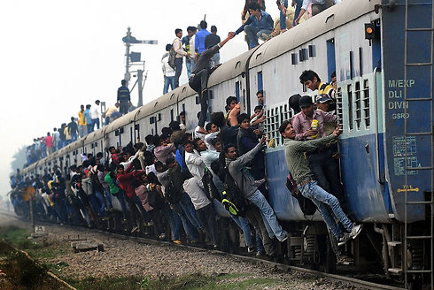 נוסעים הודים עומדים ונתלים על רכבת בפאתי ניו דלהי. אורכה של רשת המסילות של הודו הוא כ-64 אלף קילומטרים, והיא מסיעה מדי שנה יותר מחמישה מיליארד נוסעים (צילום: AFP) (צילום: AFP)