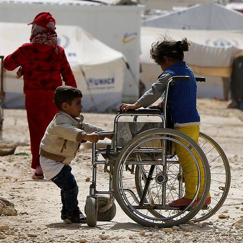 Syrian refugee children play with a wheelchair in Jordan (Photo: Reuters)