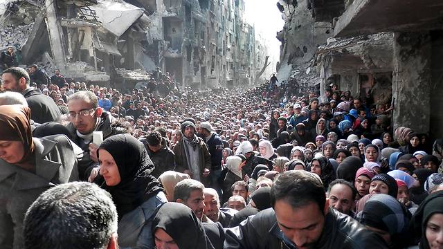 Palestinians at the besieged Yarmouk refugee camp in Damascus, queuing to receive food supplies from UNRWA (Photo: AP)