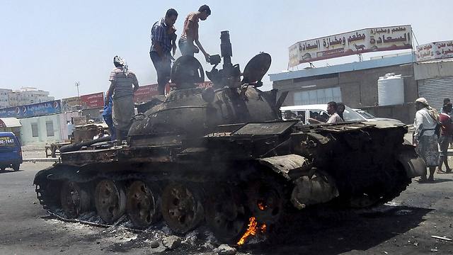 People stand on a tank that was burnt during clashes on a street in Yemen's southern port city of Aden (Photo: Reuters)