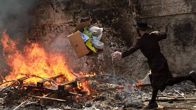 An Ultra-Orthodox Jew throws leavened items onto a fire in Jerusalem during the final preparations before the start of Passover (Photo: AFP)