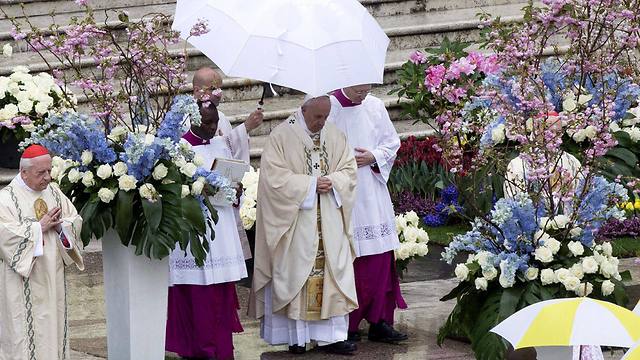  An acolyte carries an umbrella to shield Pope Francis from a shower in St. Peter's Square before he celebrates Easter Sunday Mass (Photo: EPA)