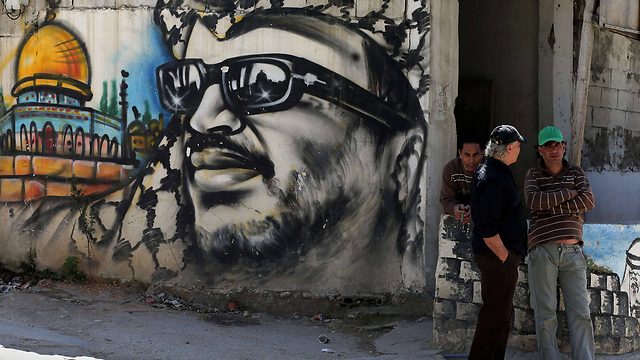 Palestinian refugees stand next to graffiti bearing a portrait of late Palestinian President Yasser Arafat at camp (Photo: AFP) (Photo: AFP)