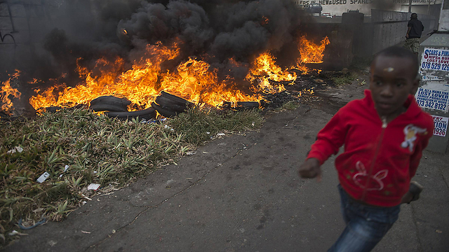 ילד בורח ממפגינים שהבעירו צמיגים (צילום: AFP) (צילום: AFP)