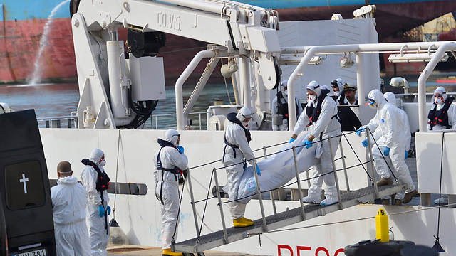 אנשי משמר החופים האיטלקי עם גופות של מהגרים שטבעו בצאתם מלוב. ארכיון (צילום: EPA) (צילום: EPA)