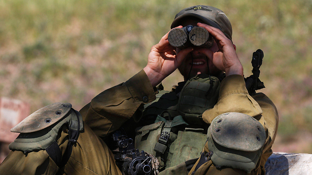An IDF soldier on the Golan looks into the nearby Syrian town of Quneitra, the site of heavy fighting. (Photo: EPA)
