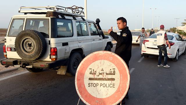 A Tunisian policeman controls cars at a checkpoint on the road to the tourist area in Houmt Souk (Photo: AFP)