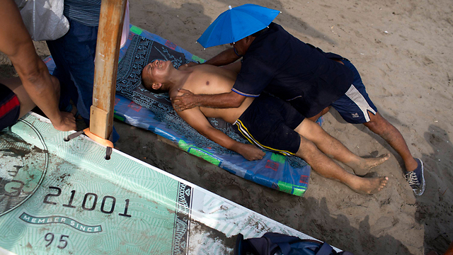 הכירופרקט פליקס רטאמוסו מטפל בחולה בחוף הים בלימה (צילום: AP) (צילום: AP)