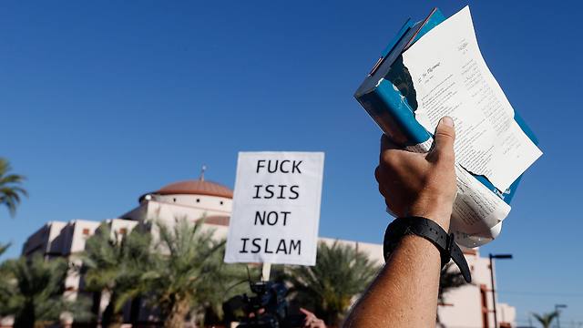 Anti-Islam protester (right) brandishing a torn copy of the Quran, faced with counterprotesters (Photo: AFP)