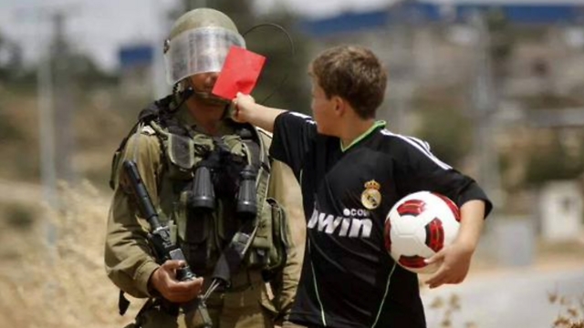 Palestinian boy showing an Israeli soldier a red card 