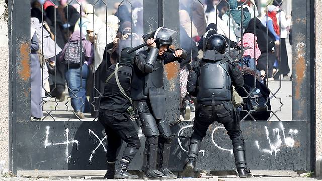 Riot police attempt to break open the entrance of the al-Azhar University campus during clashes with female students supporting Morsi, in this March 19, 2014. (Photo: Reuters)