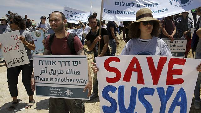 Israeli and Palestinian Peace activists holding banners during a protest in the village of Susya (Photo: EPA)