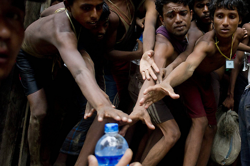 מהגרים שנמצאו בלב ים מבקשים מי שתייה במקלט זמני במדינת רקהין שבמיאנמר (צילום: AFP) (צילום: AFP)