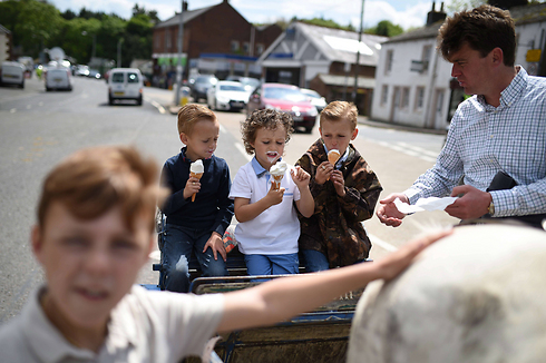 ילדים אוכלים גלידה על כרכרה במהלך יריד סוסים בעיר אפלבי אין-ווסטמורלנד בצפון אנגליה. האירוע מושך אליו אלפי מבקרים מרחבי בריטניה שמבקשים לרכוש ולמכור סוסים (צילום: AFP) (צילום: AFP)