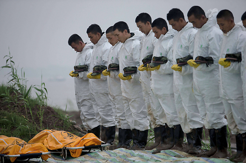 אנשי כוחות הצלה חולקים כבוד אחרון לכמה מהנספים באסון הספינה שהתהפכה וטבעה בנהר יאנגצה בסין. על הספינה היו 458 נוסעים ואנשי צוות, רק 14 ניצלו וכל היתר ככל הנראה מתו (צילום: AFP) (צילום: AFP)