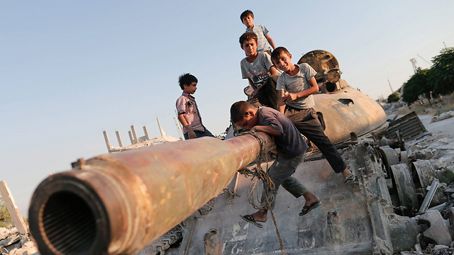 Children playing on a broken tank in Kobani (Photo: EPA)