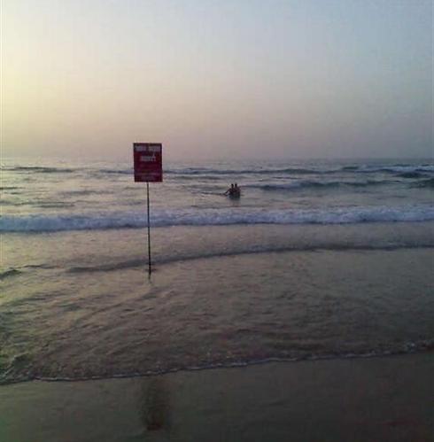 לכאורה, אלה בני הזוג שטובלים לים ליד השלט המזהיר מפני רחצה (אך לא כולל פירוט של הקנס). צילום: עיריית ראשל"צ ()