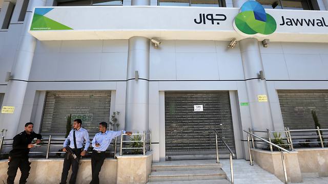 Hamas police stand in front of the closed doors of Jawwal company's office in Gaza(Photo: AFP)