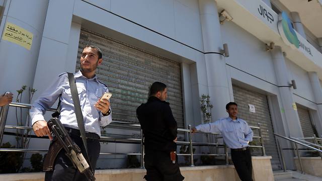 Hamas police stand in front of the closed doors of Jawwal company's office in Gaza(Photo: AFP)
