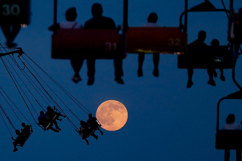 אנשים נהנים ממתקני פארק שעשועים במזרח רתרפורד, ניו ג'רזי, על רקע ירח מלא (צילום: AP) (צילום: AP)