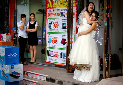 לי טינגטינג (שנייה מימין) מורמת לאוויר על ידי רעייתה תרזה שו מחוץ לסלון יופי שבו התכוננו לטקס חתונתן בבייג'יניג (צילום: AP) (צילום: AP)