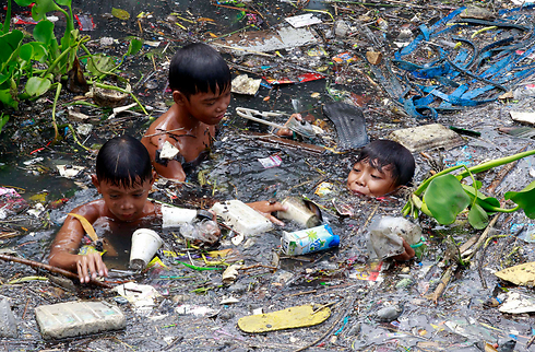 ילדים שוחים בנהר מזוהם ואוספים חומרים למחזור צפונית למנילה, בירת הפיליפינים (צילום: רויטרס) (צילום: רויטרס)
