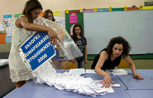 קלפי הצבעה מרוקנת על ידי פקידה לאחר סגירת הקלפיות באתונה. ביום ראשון הצביעה יוון במשאל עם על תוכנית החילוץ האירופית. רוב היוונים הצביעו נגד הסכם הצנע (צילום: רויטרס) (צילום: רויטרס)