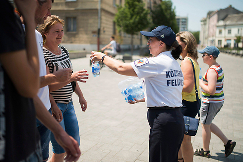 פקחית מחלקת בקבוקי מים חינם לעוברים ושבים בהונגריה (צילום: EPA) (צילום: EPA)