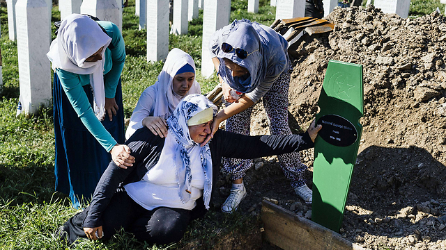 אישה בוסנית ליד הקבר הטרי שבו נטמנה אחת הגופות שזוהו לאחרונה (צילום: AFP) (צילום: AFP)