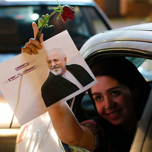 עם תמונת שר החוץ מוחמד זריף שהפך לגיבור החגיגות באיראן (צילום: EPA) (צילום: EPA)