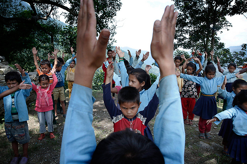 תלמידי בית ספר נפאלים משתתפים בשיעור התעמלות. התלמידים בכפר פאנגרטאר לומדים במבנה זמני שהוקם מעצי במבוק לאחר שבית הספר שלהם נהרס ברעידת האדמה העזה לפני שלושה חודשים (צילום: EPA) (צילום: EPA)