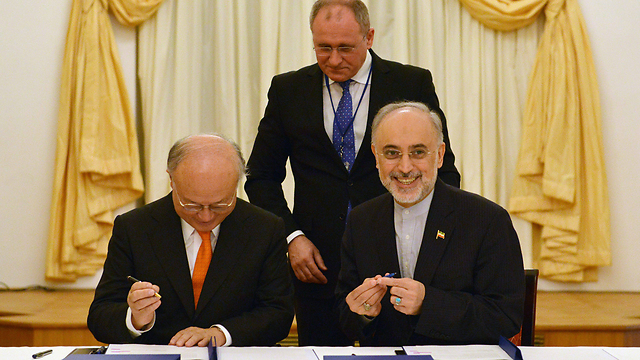 לאיראנים יש סיבה לחייך. שר החוץ האיראני זריף (מימין) חותם על ההסכם לצד ראש סבא"א אמאנון (צילום: EPA) (צילום: EPA)