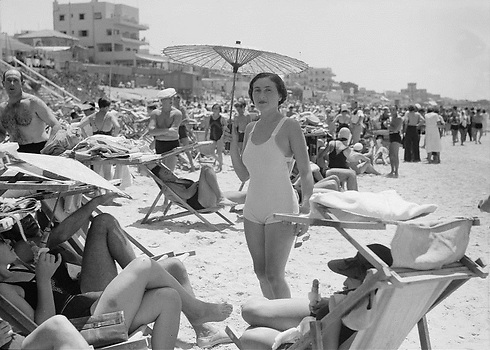 המונים פוקדים את חוף הים, במרכז אשת חברה אוחזת במטריית נייר, משמאל מלון "קטה דן", 1934 (צילום: אריק ואדית מאטסון, ספריית הקונגרס) (צילום: אריק ואדית מאטסון, ספריית הקונגרס)