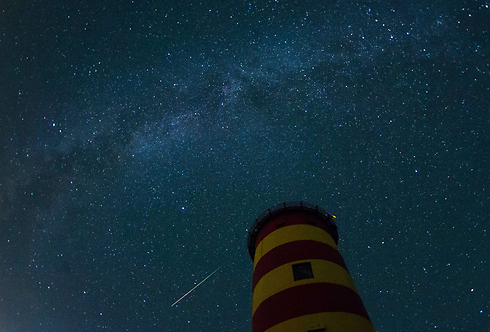 A meteor crosses the sky behind the lighthouse in Pilsum, Germany. (Photo: AFP)