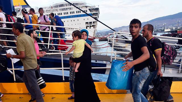 פליטים ומהגרים עולים למעבורת בדרכם לאתונה. ברקע: הספינה (צילום: gettyimages) (צילום: gettyimages)