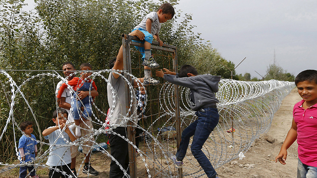 גדר התיל לא עוצרת בעדם. מהגרים נכנסים להונגריה (צילום: רויטרס) (צילום: רויטרס)