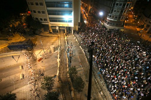 Lebanese anti-government protesters, center, crossed the first barrier of the barbed wires that block the road to the government building, as they throw stones and bottles (Photo: AP)