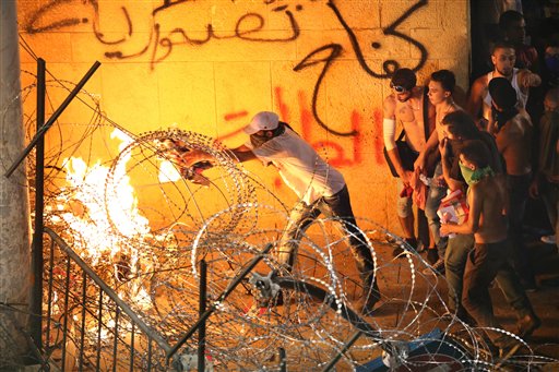 Lebanese anti-government protesters burn the razor wires that block the road to the government building (Photo: AP)