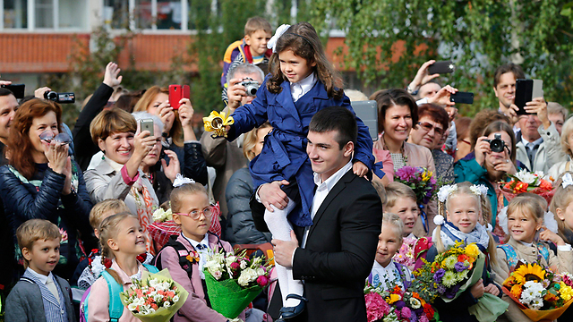 תלמידים מביאים פרחים למוריהם במוסקבה, ילדה מצלצלת בפעמון (צילום: EPA) (צילום: EPA)