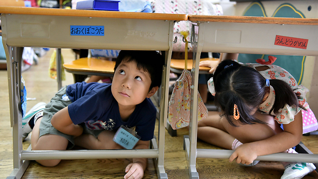 ילדים יפנים בתרגיל למקרה של רעידת אדמה או אסון אחר, בכיתה בטוקיו (צילום: AFP) (צילום: AFP)