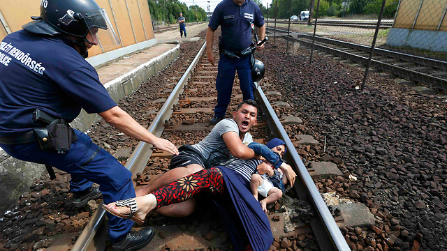 Police wrestle family protesting being taken to nearby refugee camp in Bicske, Hungary on Thursday (Photo: Reuters)