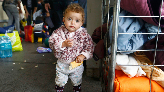 בת למשפחת מהגרים אוכלת לחם שחולק לפליטים עם הגעתם לווינה (צילום: רויטרס) (צילום: רויטרס)